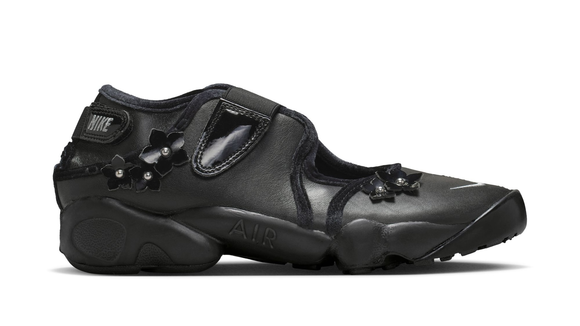 A black Nike sneaker with a unique design, featuring floral embellishments and a split-toe style.