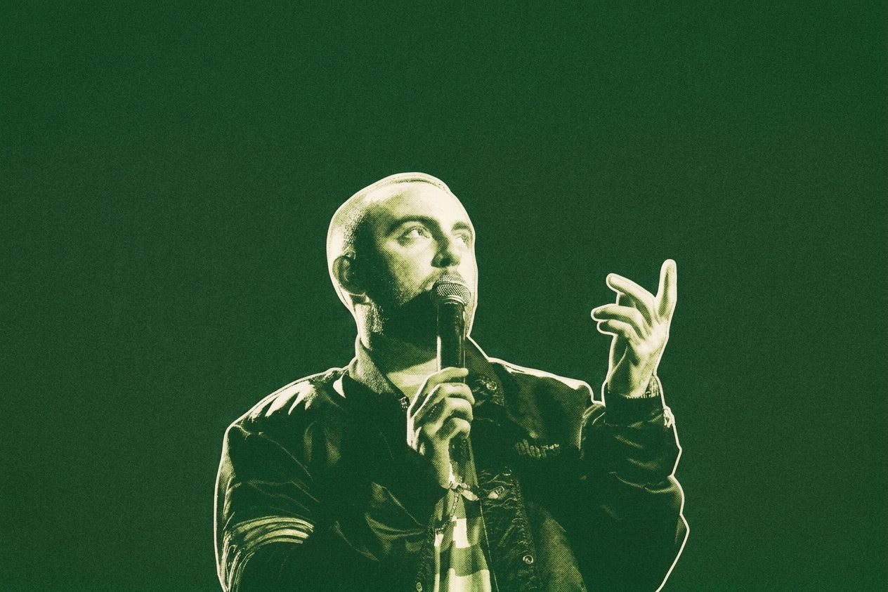 Mac Miller holding a microphone on stage, wearing a dark jacket, under dramatic lighting with a smoky background.