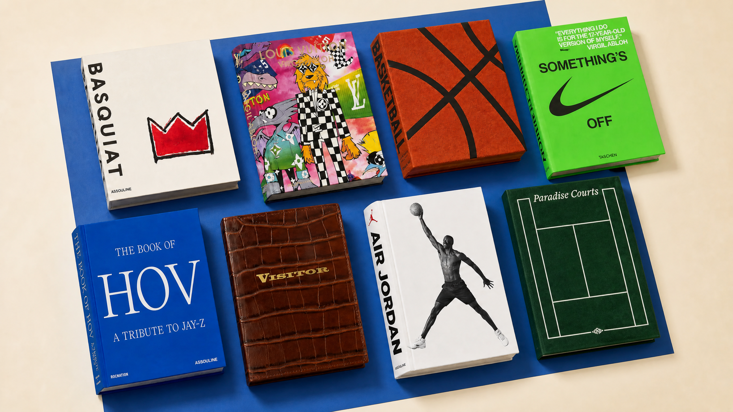 A collection of seven stylish books with varied designs, including themes like Basquiat, Air Jordan, and Jay-Z, arranged on a blue surface.