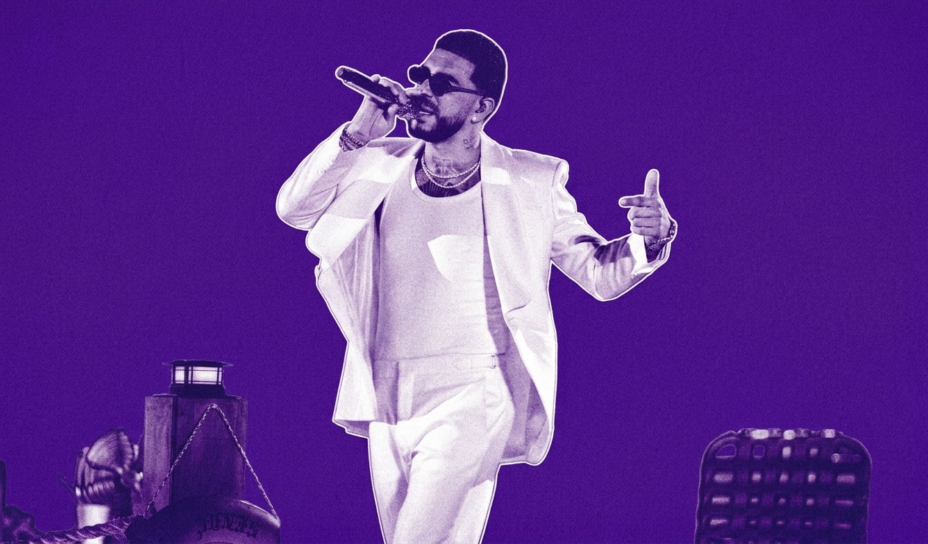 Ryan Castro in a white suit and sunglasses performs on stage with a microphone, set against a purple background.