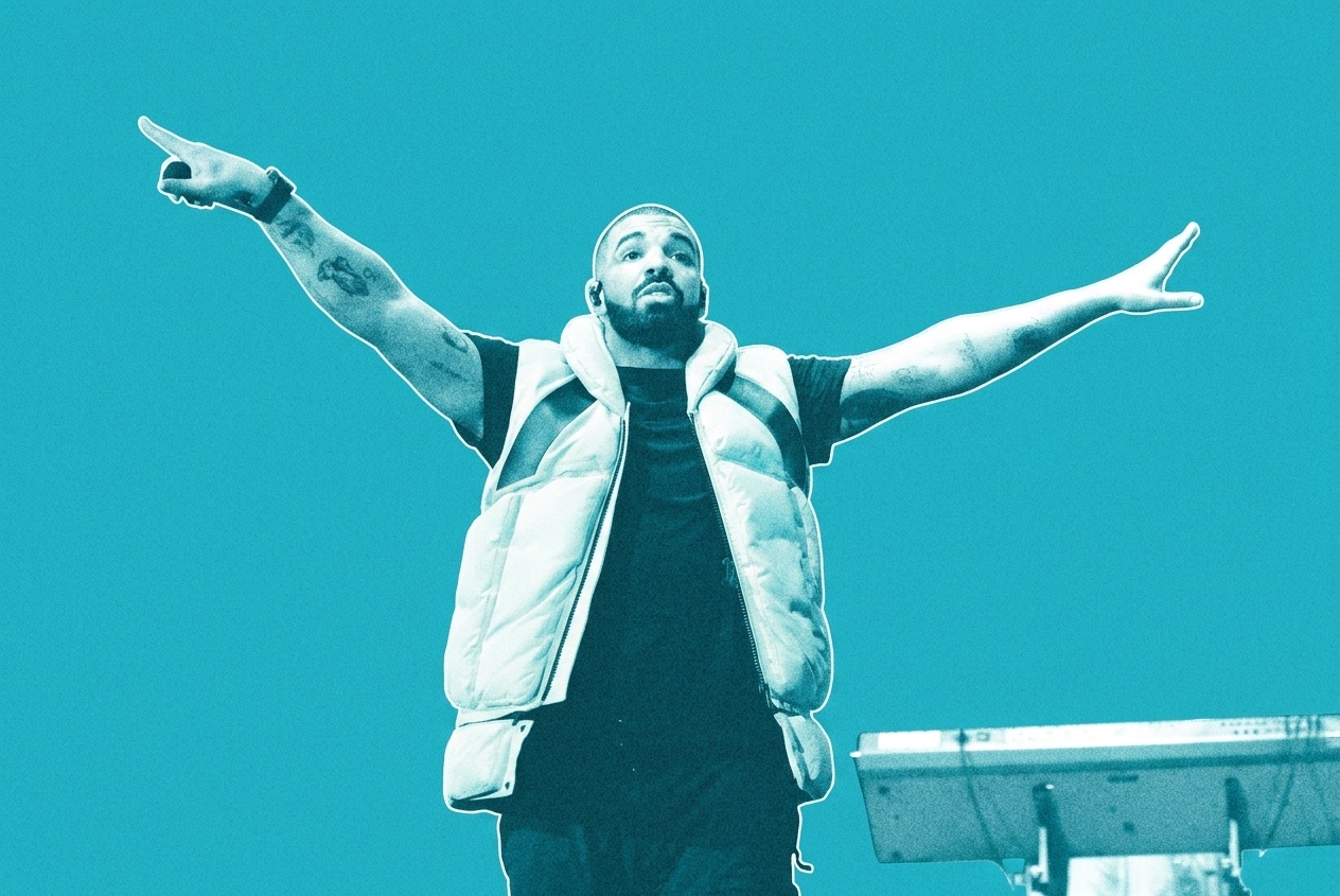Drake performing on stage, wearing a yellow vest, arms outstretched against a blue-lit background.