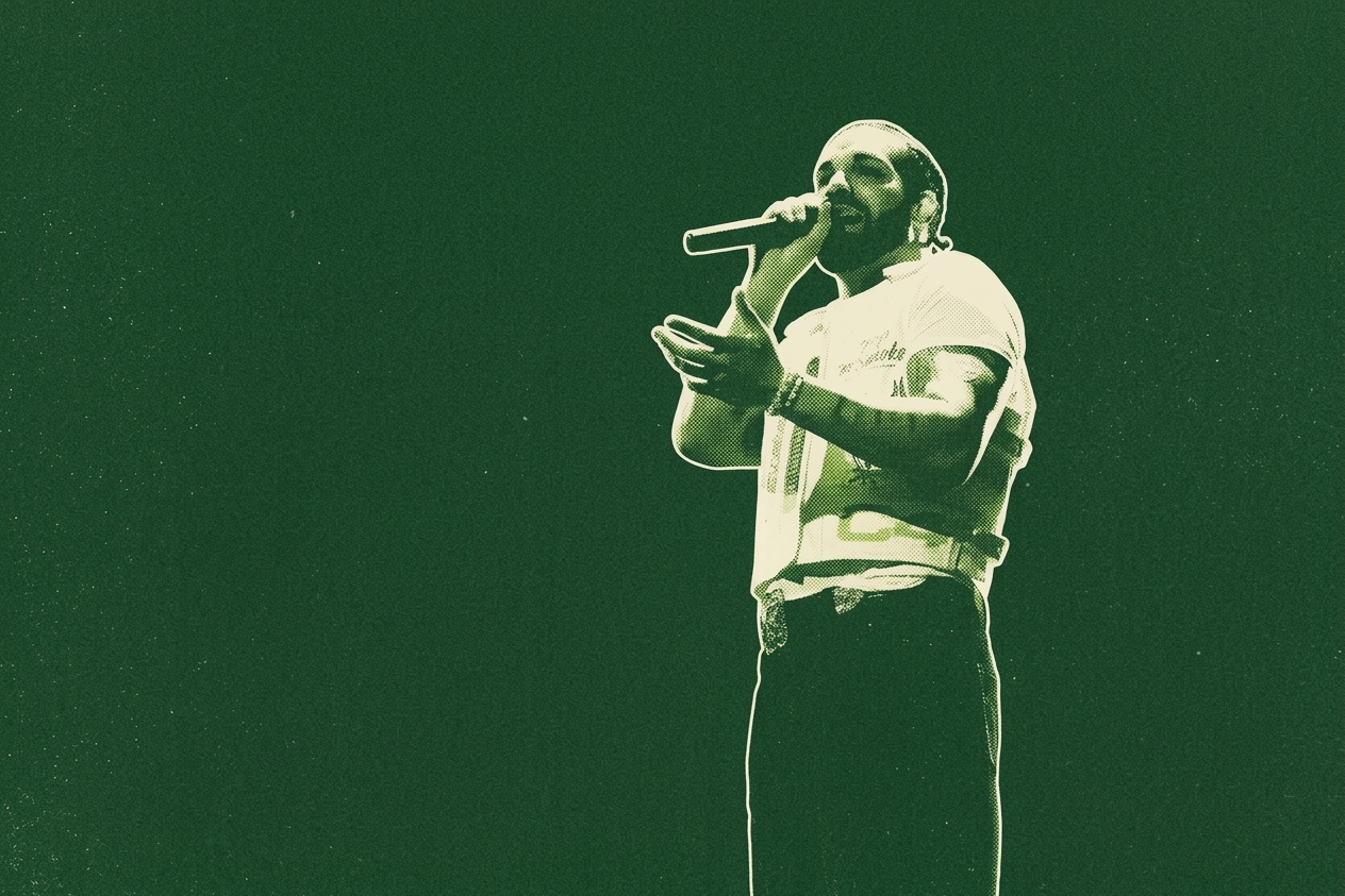 A person performing on stage with a microphone, wearing a white shirt and dark pants, set against a green background.