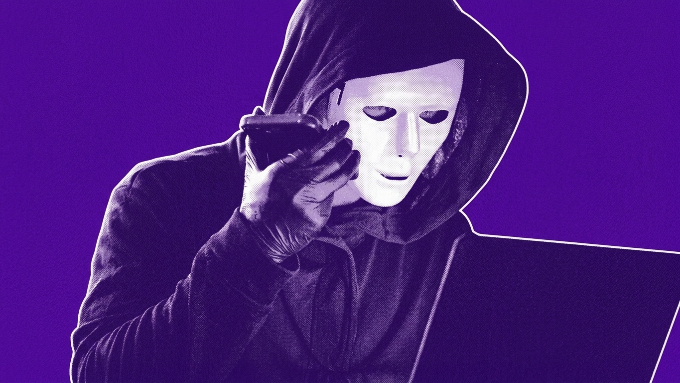 A person in a white mask and hoodie uses a phone and laptop, with binary code overlayed, in a dimly lit room.
