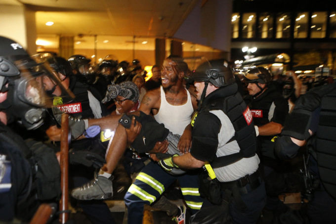 Police and protesters carry a wounded demonstrator.