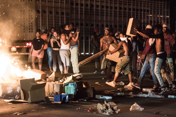 Protesters tossing cargo from tractor trailers onto a fire on I-85