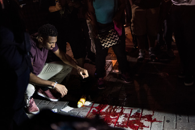 A man looks at blood on the sidewalk.