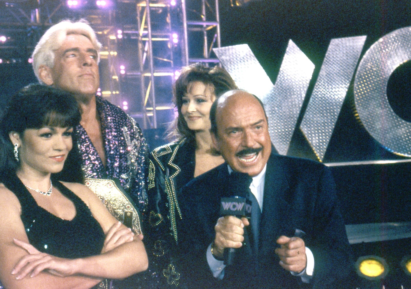 Woman, Ric Flair, Miss Elizabeth and Gene Okerlund circa 1998 during a WCW broadcast.