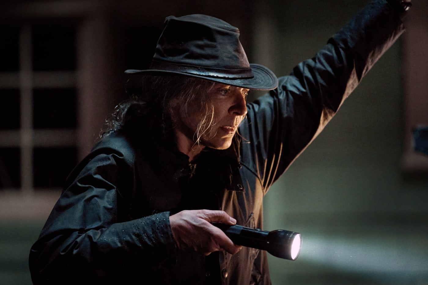 A woman wears all black and holds a flashlight.