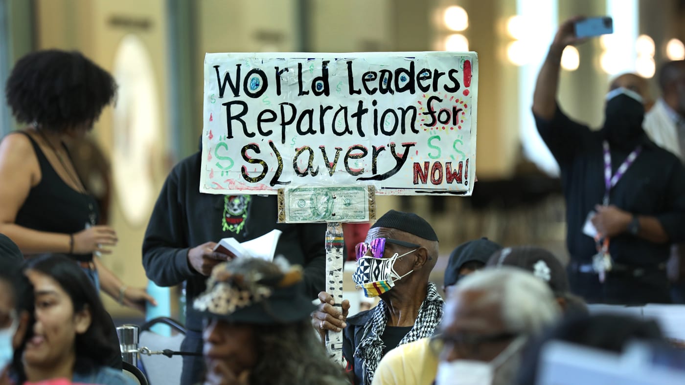 Los Angeles long time resident, Walter Foster, age 80, holds up a sign as the Reparations Task Force meets