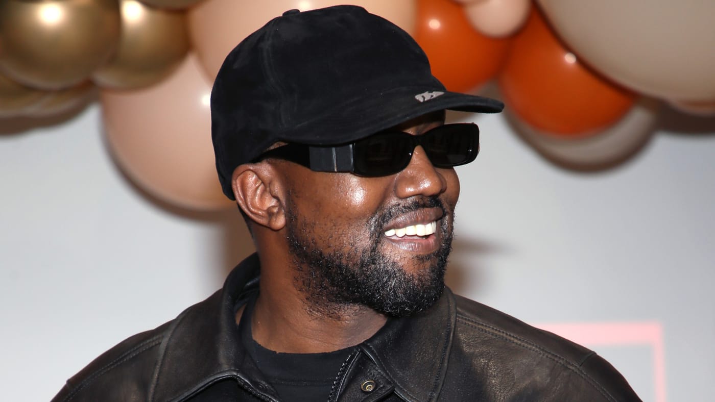 Ye smiles while wearing a hat and sunglasses.