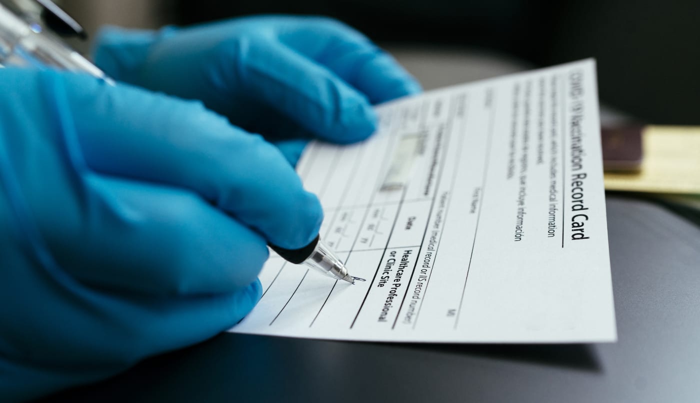 A doctor filling out a COVID 19 vaccination card