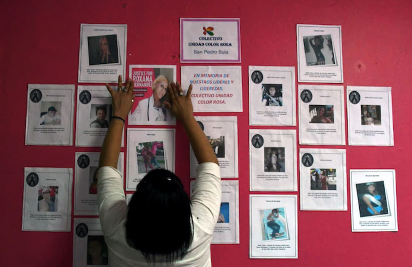 A member of the Pink Unity Collective places a poster on a board, demanding justice.
