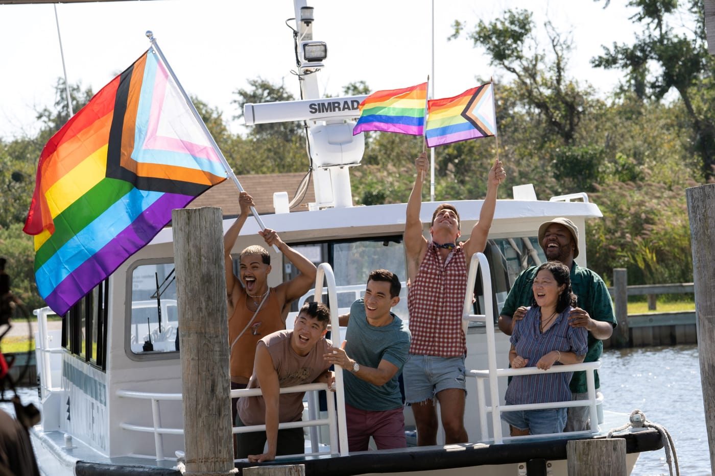 people on a boat waving gay pride flag