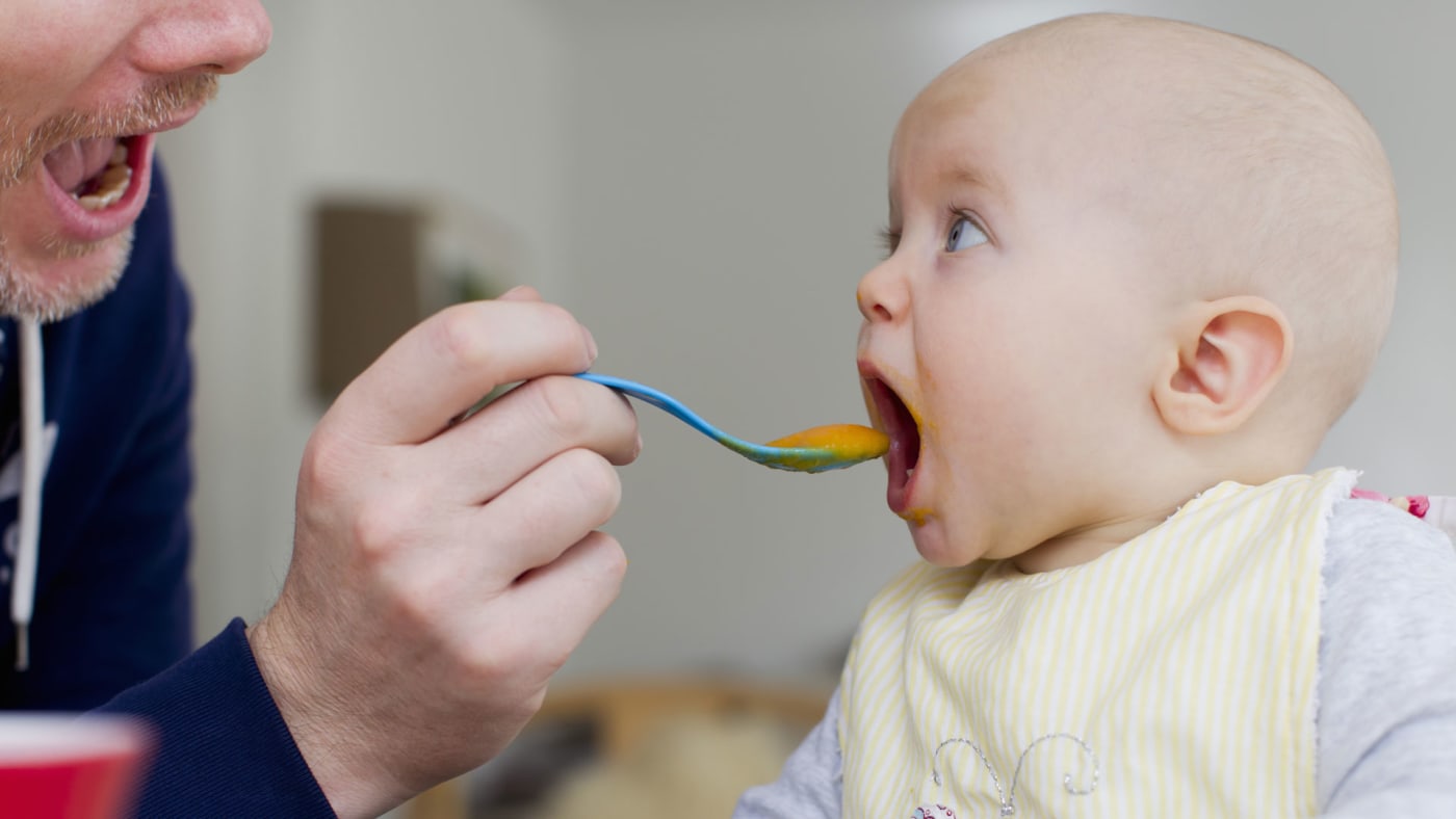 Father spoon feeding baby daughter.