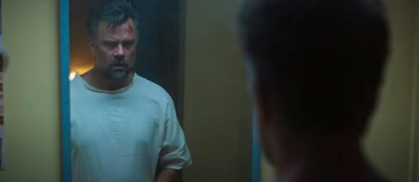 A man stares at his head in the mirror.