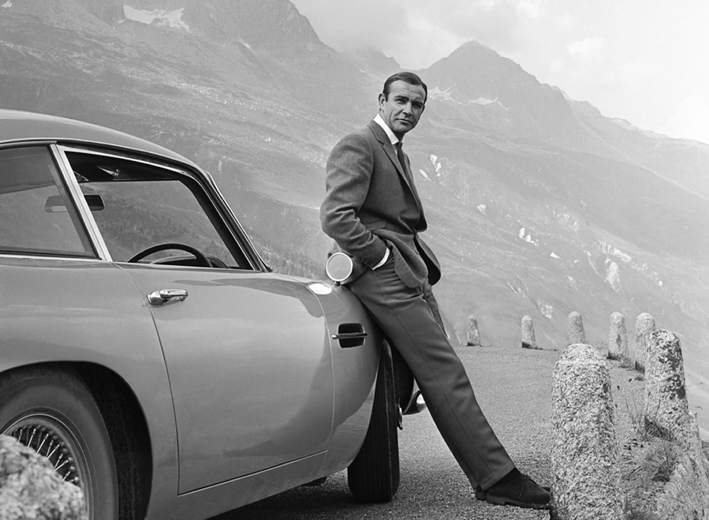 Sean Connery poses as James Bond next to his Aston Martin DB5 in a scene from 'Goldfinger'