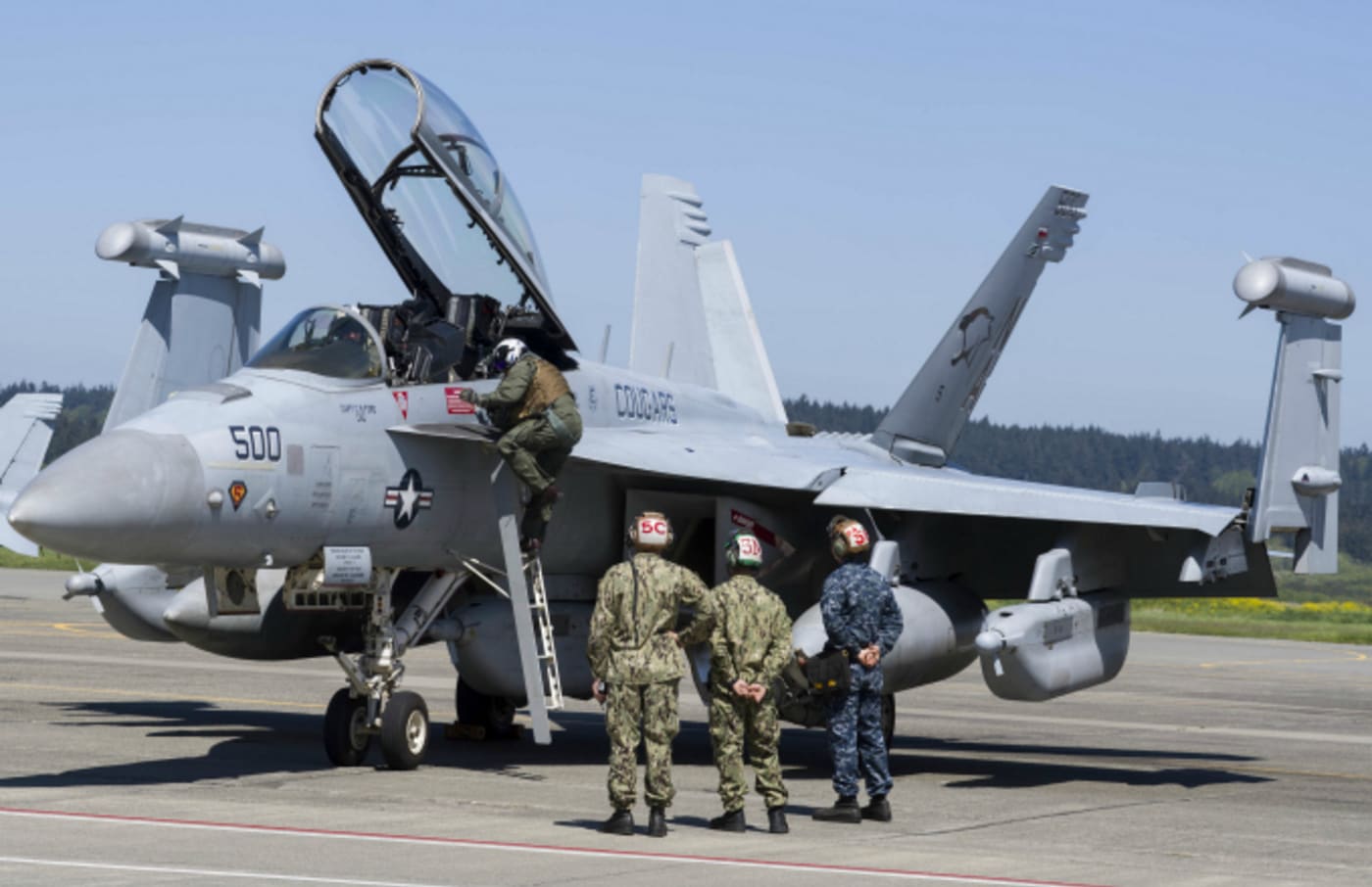 Three technicians watching as pilot climbs to his EA 18G Growler aircraft