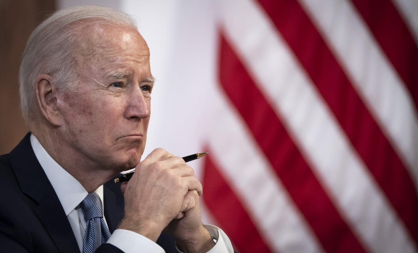 Joe Biden holding a pen at desk