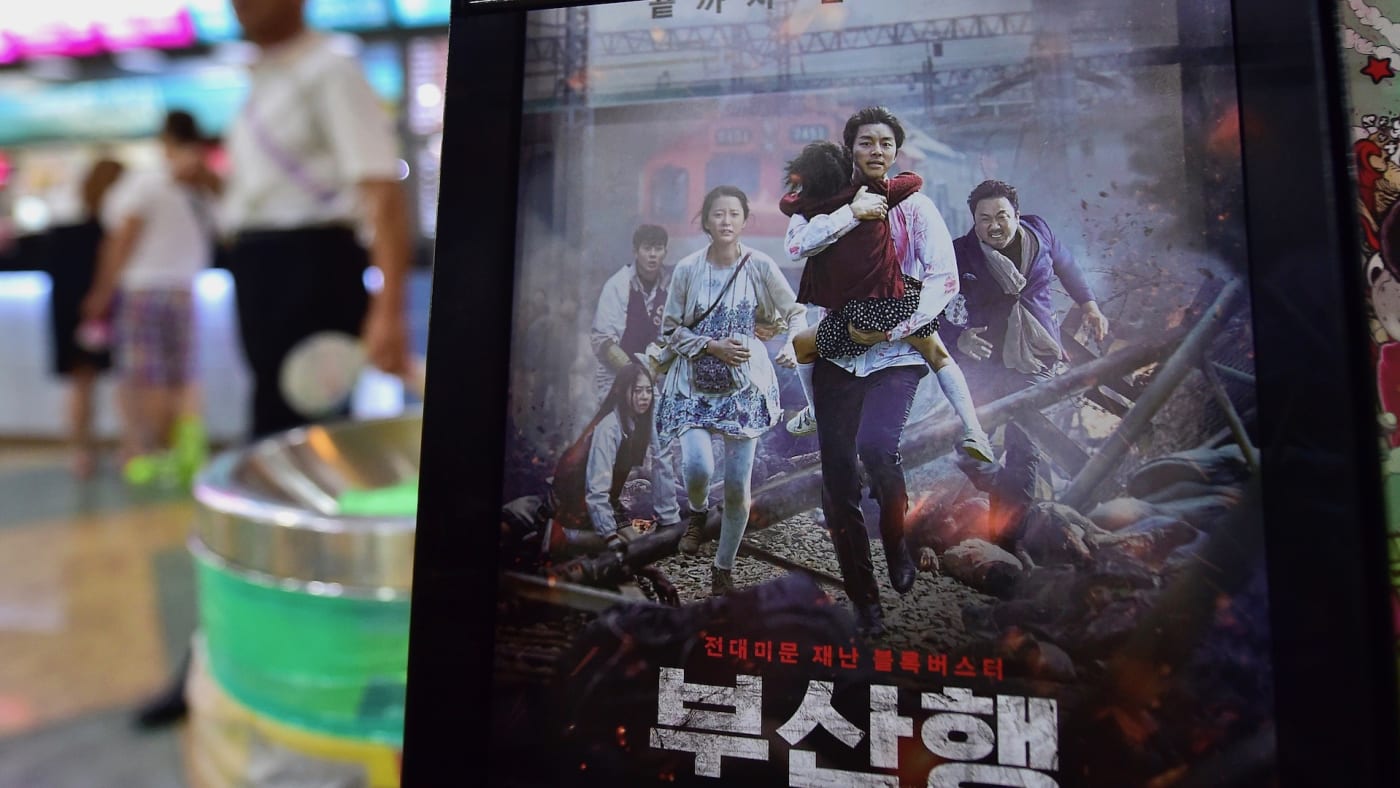 A man walks past a poster of 'Train to Busan'