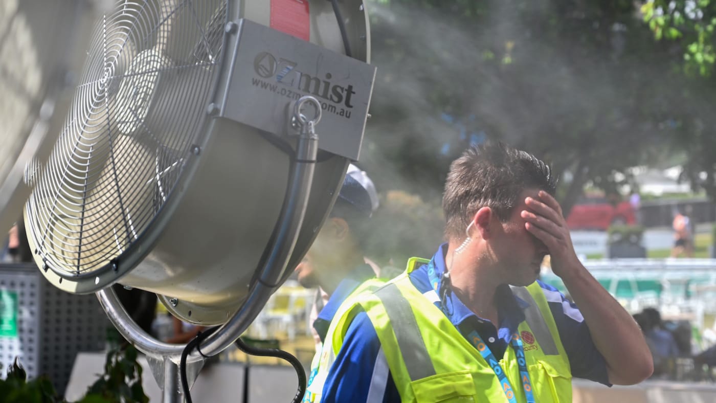 man cools down in front of a mist fan for relief from the hot weather.