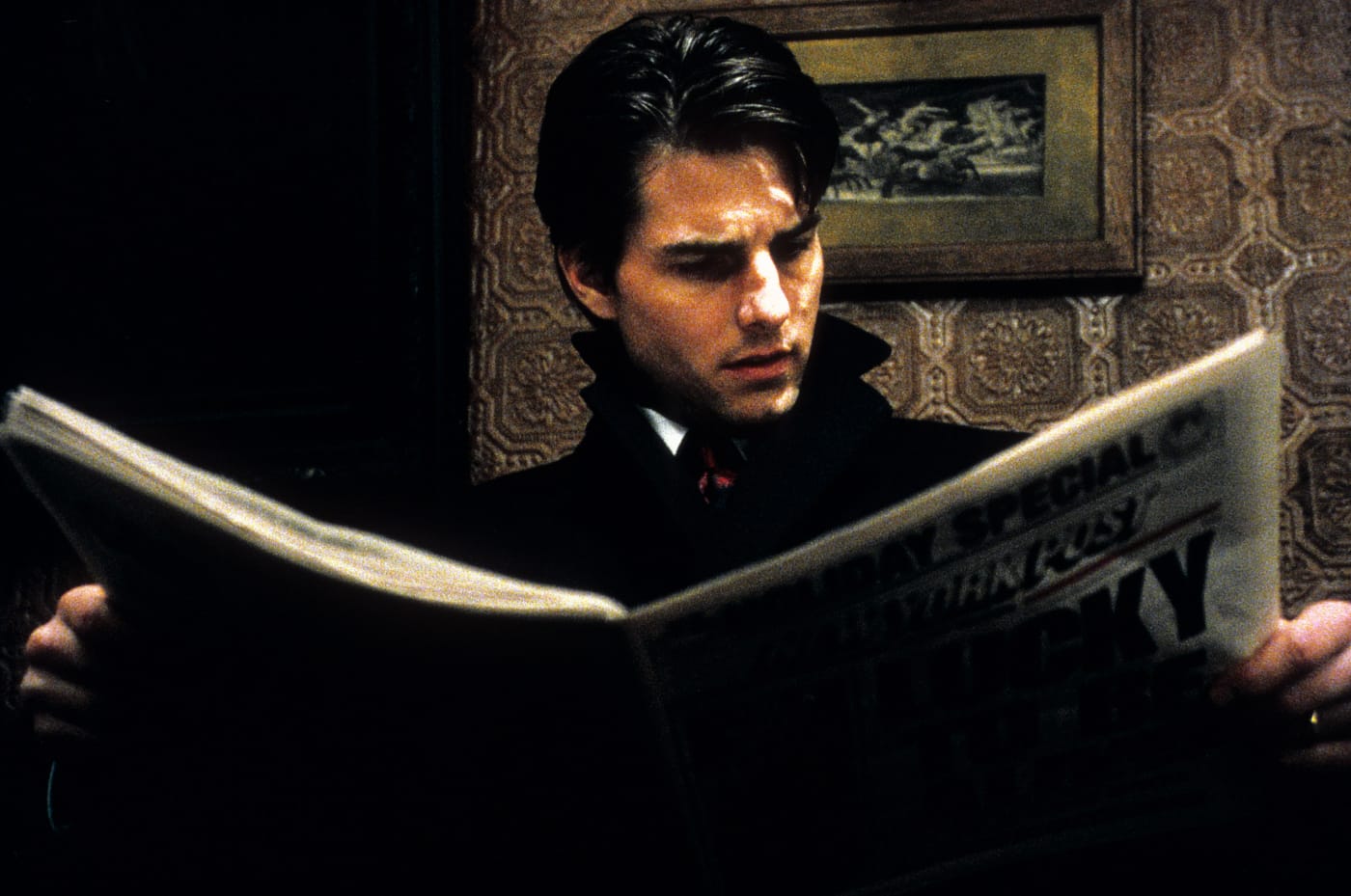 Tom Cruise looks at a newspaper.