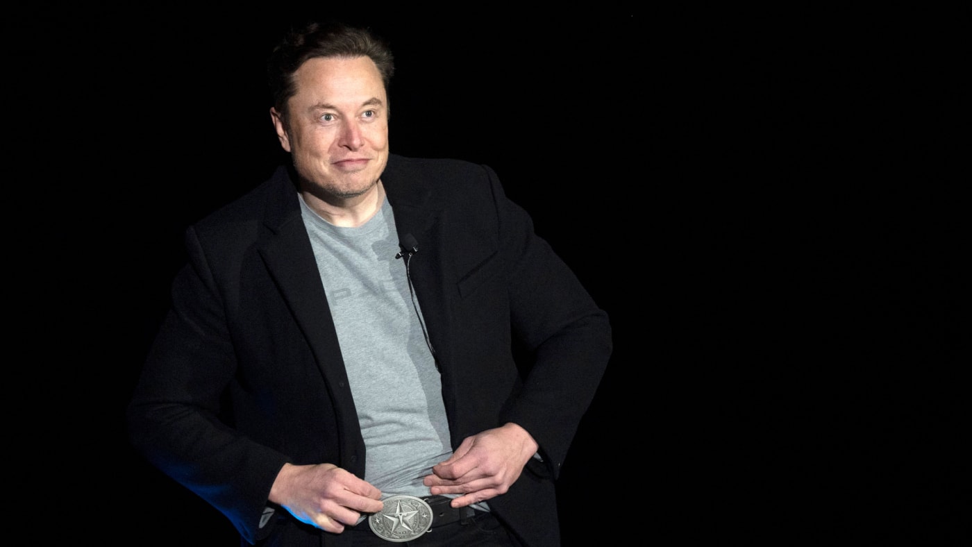 Elon Musk is pictured standing in front of other people