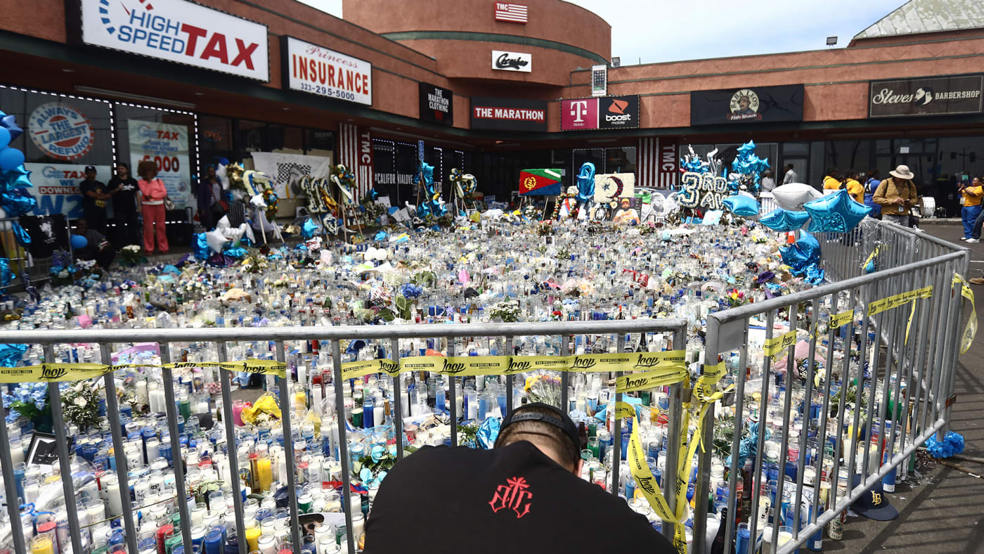 A man kneels at a memorial set up outside The Marathon Clothing store