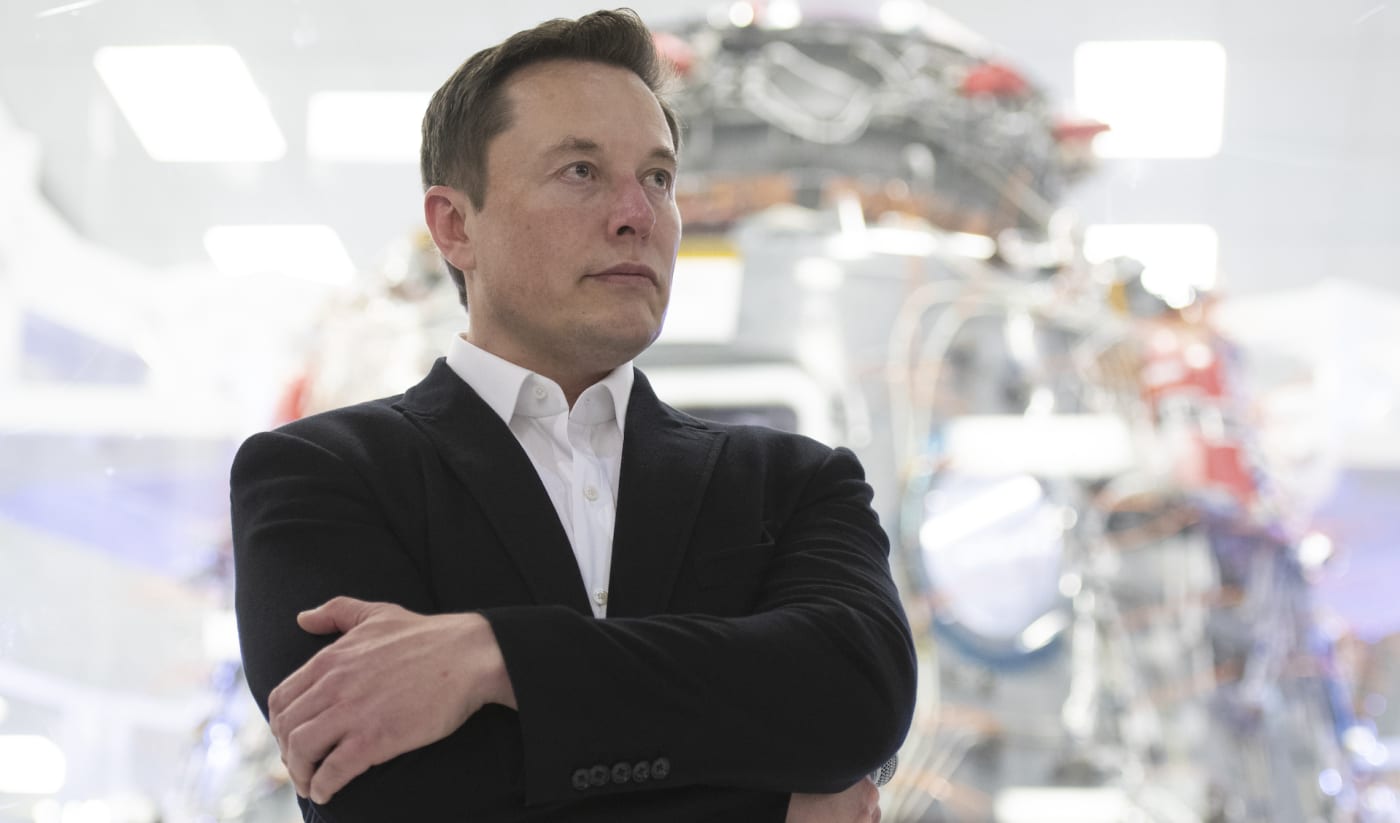 Elon Musk standing with arms crossed