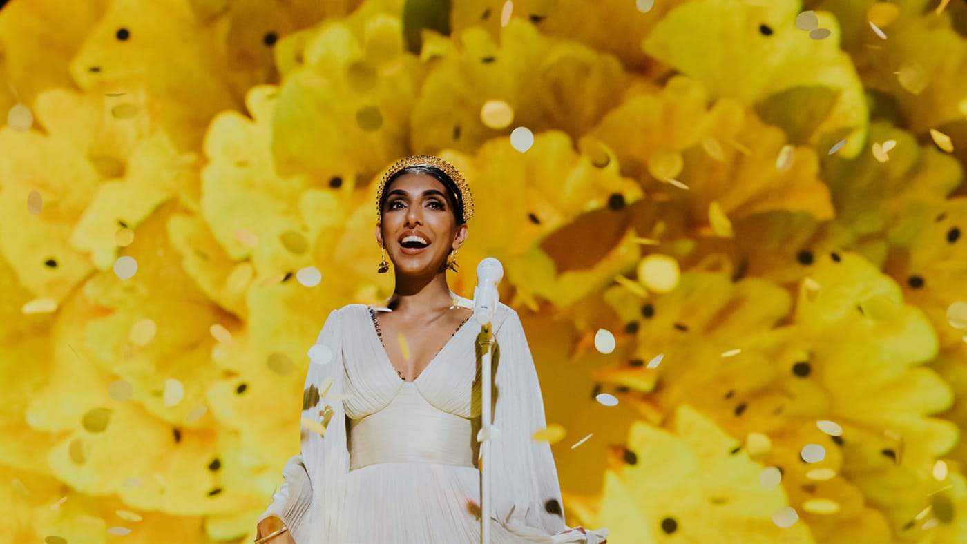 Rupi Kaur standing in front of a yellow flower
