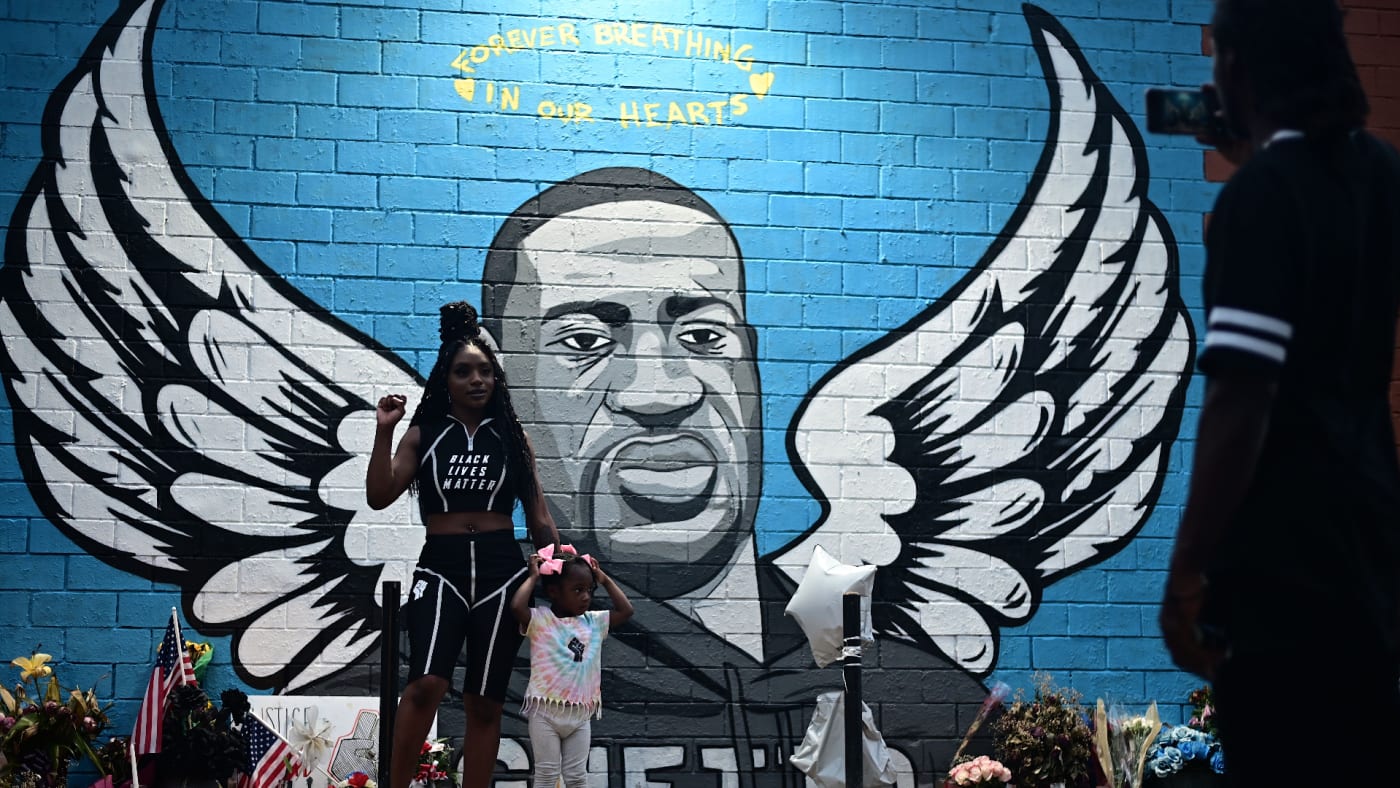 People stand in front of a mural of George Floyd in Houston, Texas.