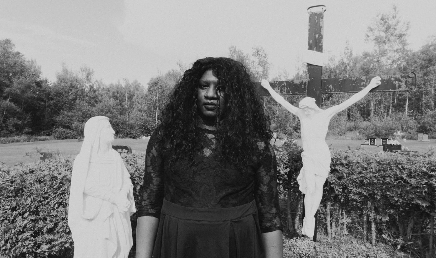 Montreal rapper Backxwash poses in field with crucifix