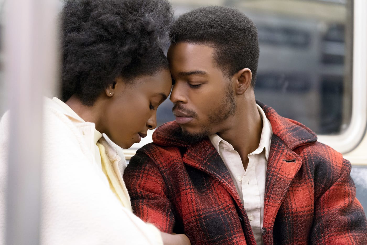 A black couple touch foreheads while on the subway.