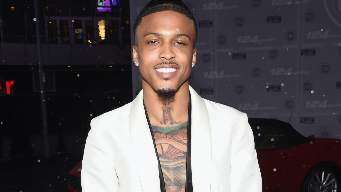 august alsina at a premiere in front of a car backdrop
