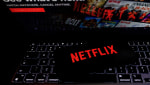 Netflix logo is displayed on a mobile phone screen with Netflix website in a background